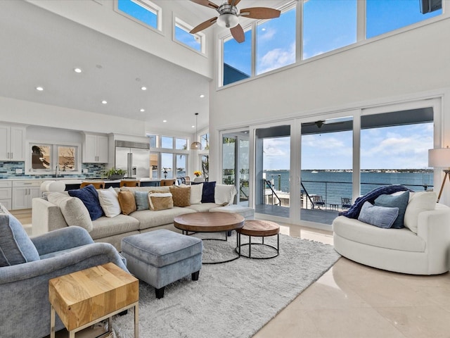 living room with a water view, ceiling fan, sink, and light tile patterned floors