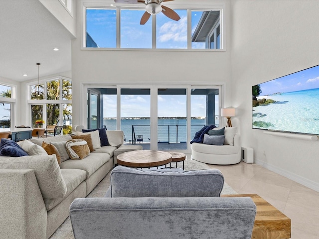 living room with ceiling fan, a towering ceiling, and light tile patterned floors