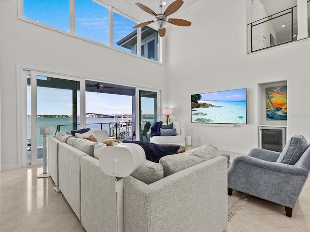 living room featuring a water view, light tile patterned floors, and ceiling fan