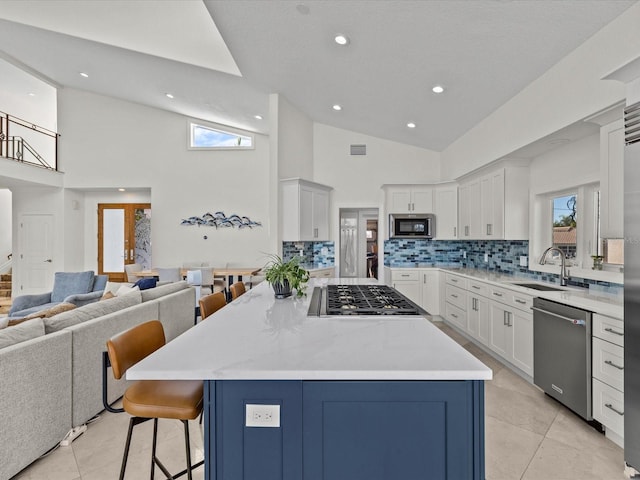 kitchen with white cabinetry, appliances with stainless steel finishes, sink, and a kitchen bar