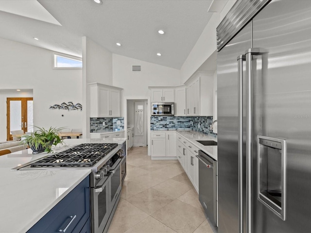 kitchen with blue cabinets, sink, white cabinets, and premium appliances