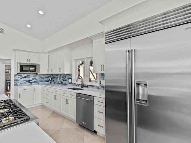 kitchen featuring tasteful backsplash, white cabinetry, appliances with stainless steel finishes, and sink