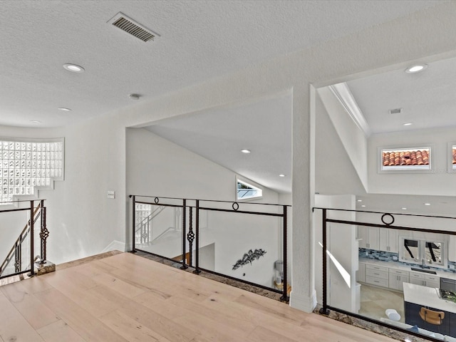 corridor featuring a wealth of natural light, a textured ceiling, and light wood-type flooring