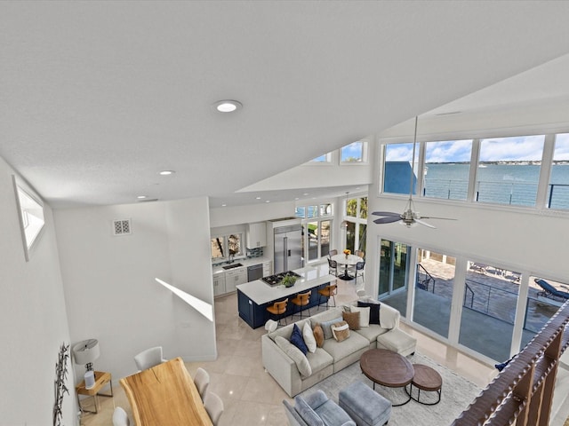 tiled living room with a water view, plenty of natural light, and sink