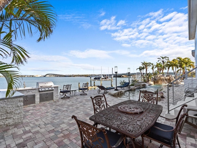 view of patio with a grill, sink, exterior kitchen, and a water view