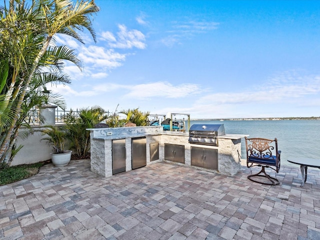 view of patio featuring a water view, an outdoor kitchen, and area for grilling