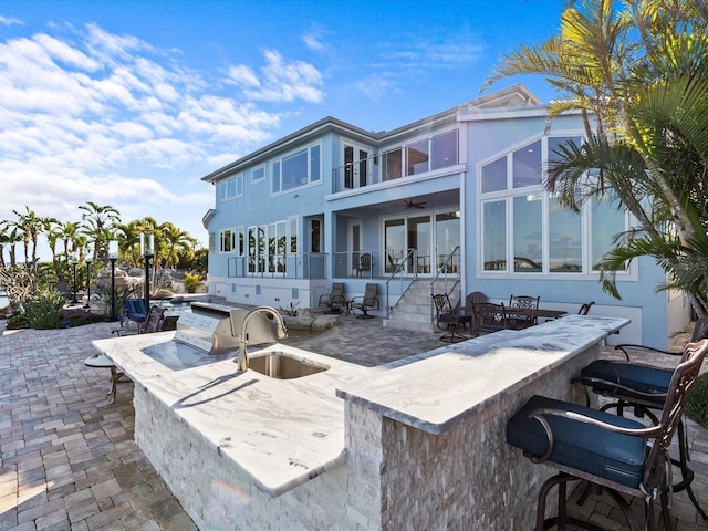 back of property with exterior kitchen, an outdoor wet bar, ceiling fan, and a patio area