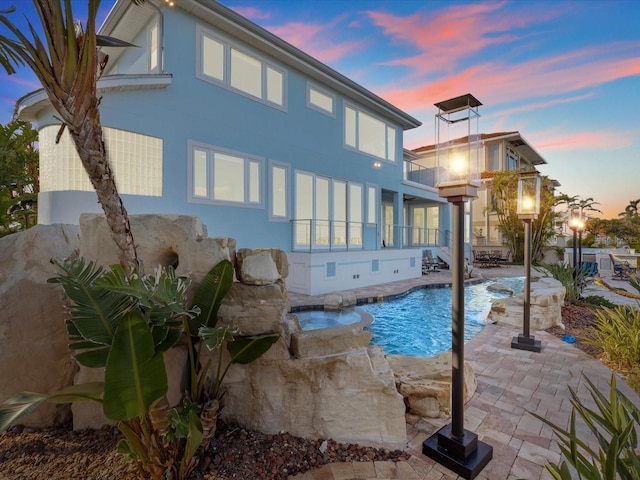 exterior space featuring pool water feature, a balcony, and a patio area