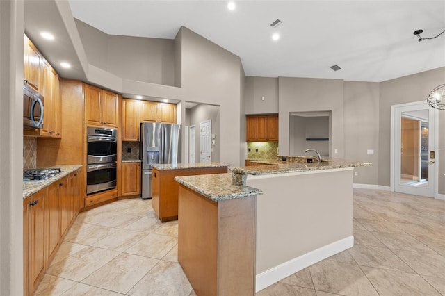 kitchen featuring light stone counters, appliances with stainless steel finishes, a center island, and light tile patterned flooring