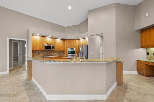 kitchen featuring stainless steel appliances, tasteful backsplash, light stone counters, and kitchen peninsula