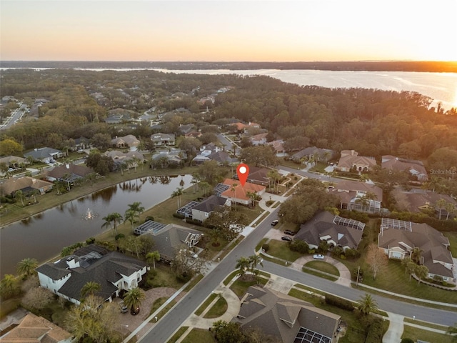 aerial view at dusk featuring a water view