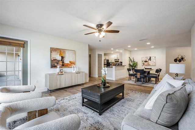 living room with ceiling fan and light hardwood / wood-style flooring