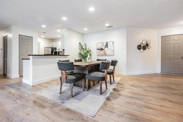 dining room featuring a textured ceiling and light hardwood / wood-style flooring