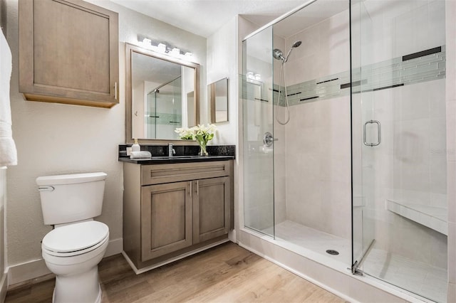 bathroom with wood-type flooring, vanity, an enclosed shower, and toilet