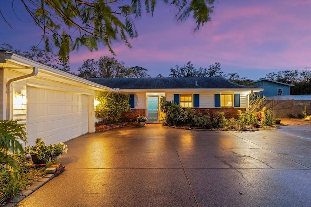 single story home with a garage, concrete driveway, brick siding, and fence