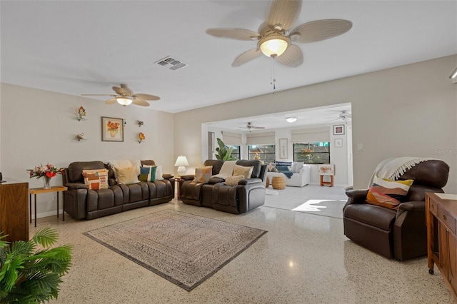 living area with light speckled floor, a ceiling fan, visible vents, and baseboards