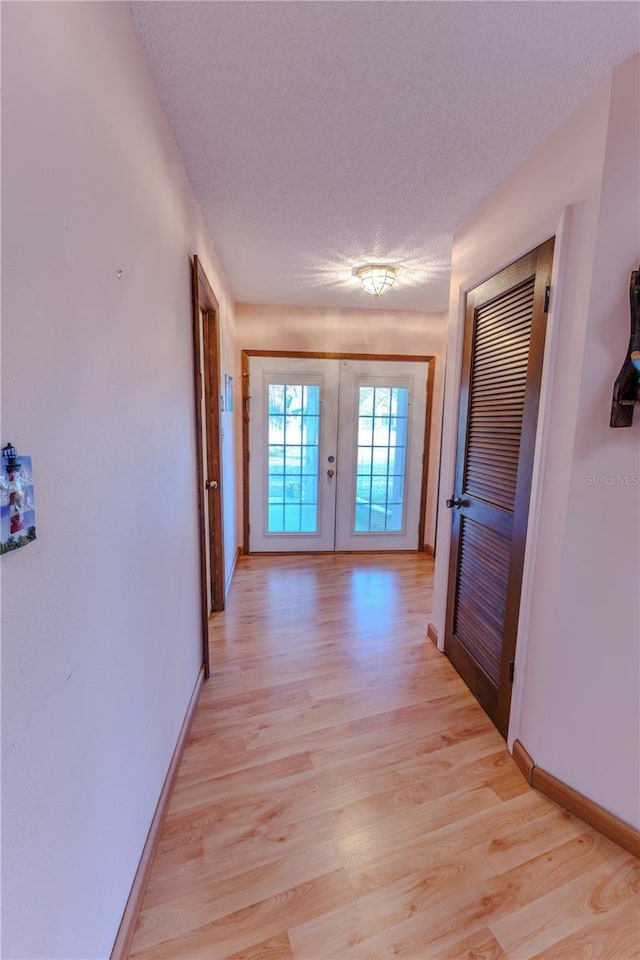 hallway featuring light wood-type flooring and a textured ceiling