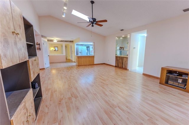 unfurnished living room featuring ceiling fan, vaulted ceiling with skylight, and light wood-type flooring