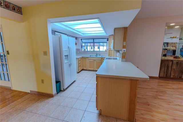 kitchen with kitchen peninsula, light wood-type flooring, light brown cabinets, and white fridge with ice dispenser