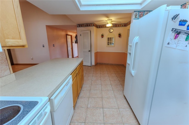 kitchen with a skylight, light tile patterned floors, ceiling fan, light brown cabinets, and white appliances