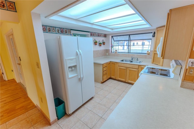 kitchen featuring light tile patterned flooring, sink, a skylight, light brown cabinets, and white appliances