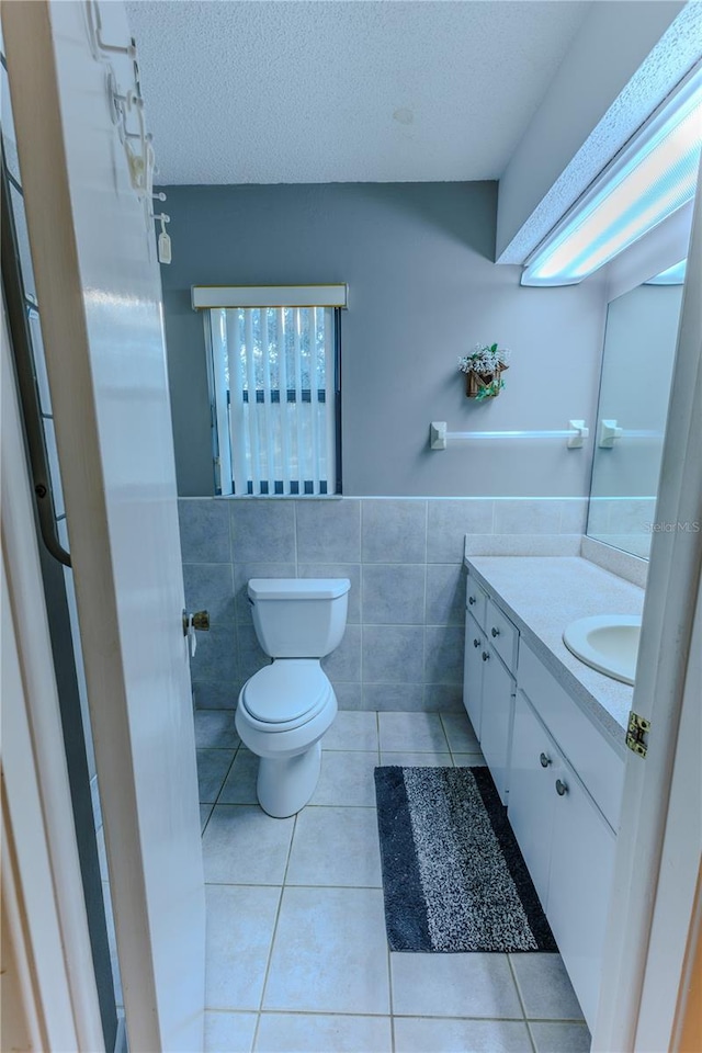 bathroom with tile walls, vanity, tile patterned floors, and a textured ceiling