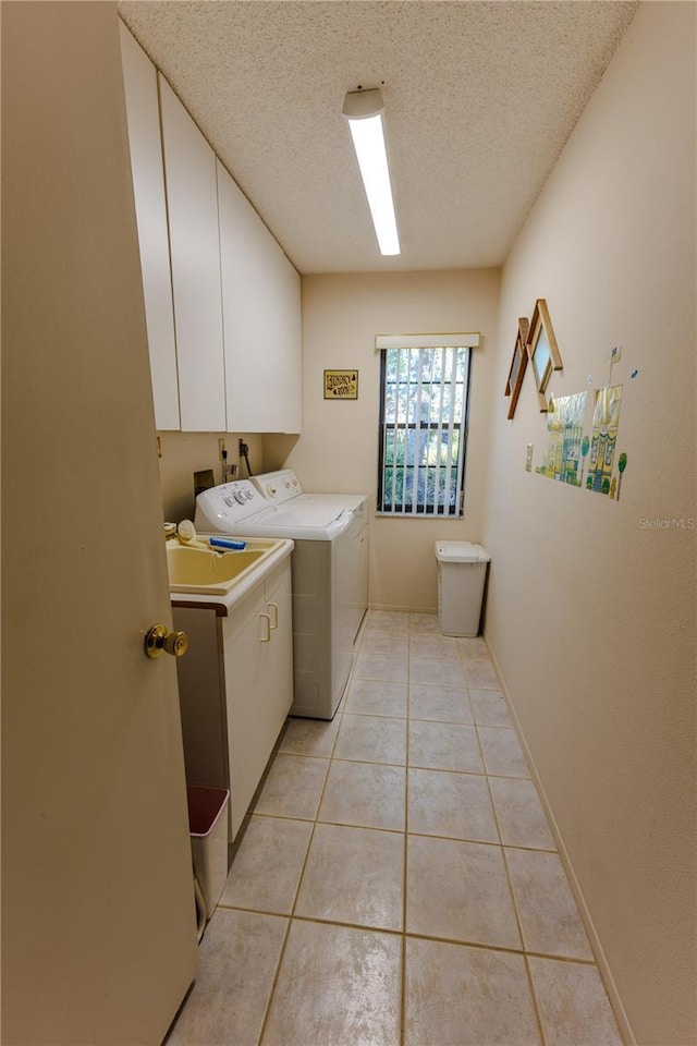 laundry room featuring cabinets, separate washer and dryer, a textured ceiling, and light tile patterned floors