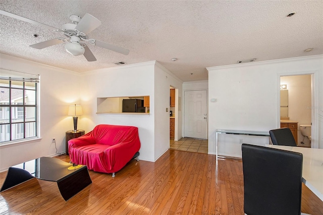 living room featuring ceiling fan, crown molding, wood-type flooring, and a textured ceiling