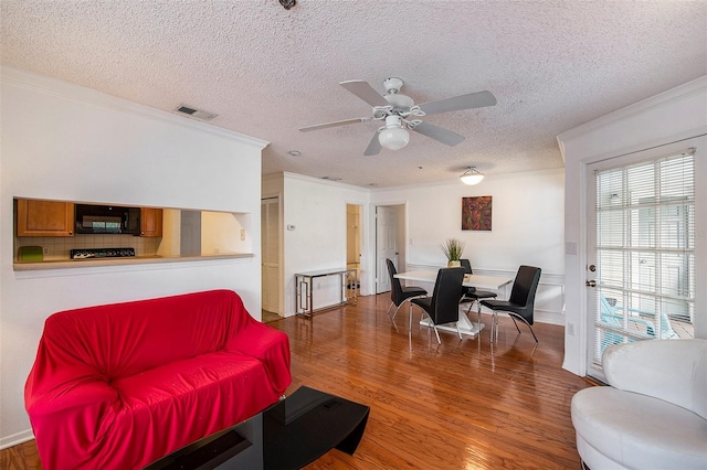 living room featuring crown molding, dark wood-type flooring, ceiling fan, and a textured ceiling