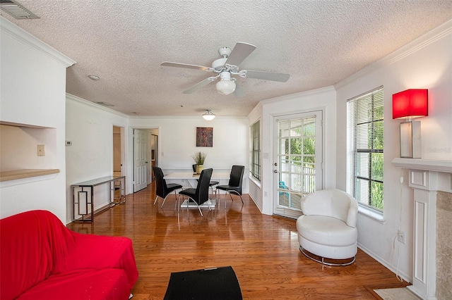 living room featuring hardwood / wood-style flooring, crown molding, ceiling fan, and a textured ceiling