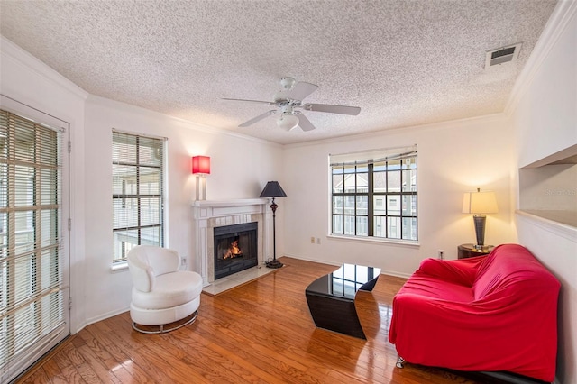 living room with hardwood / wood-style flooring, crown molding, a textured ceiling, and a fireplace