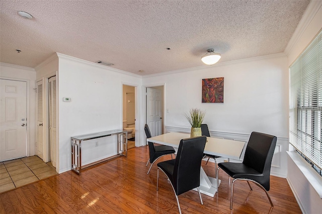 dining room with hardwood / wood-style flooring, ornamental molding, and a textured ceiling