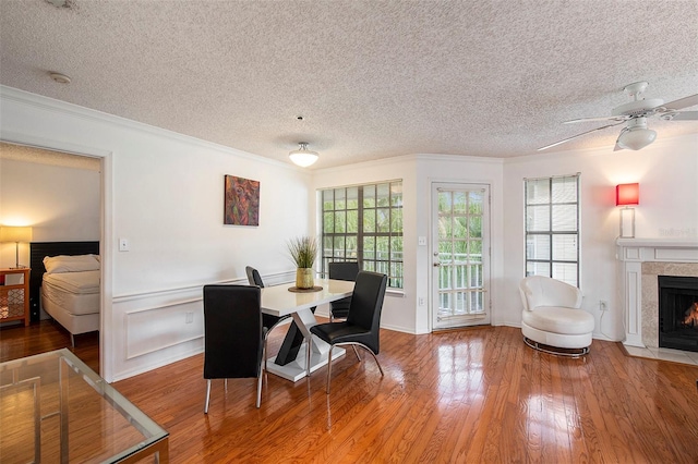 dining space featuring wood-type flooring, a healthy amount of sunlight, crown molding, and a fireplace