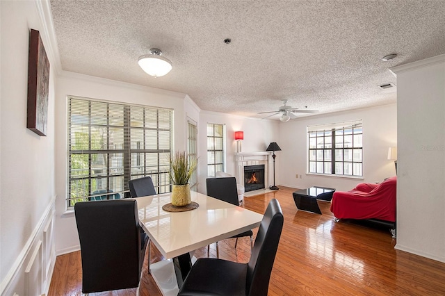 dining room featuring hardwood / wood-style flooring, ornamental molding, a textured ceiling, and ceiling fan