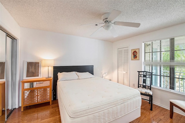 bedroom featuring ceiling fan, wood-type flooring, a closet, and a textured ceiling