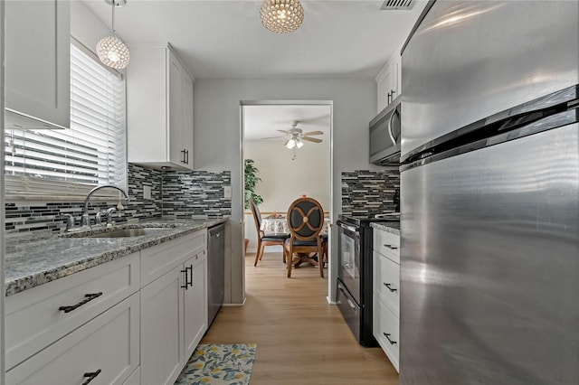 kitchen featuring sink, white cabinetry, hanging light fixtures, stainless steel appliances, and light stone countertops