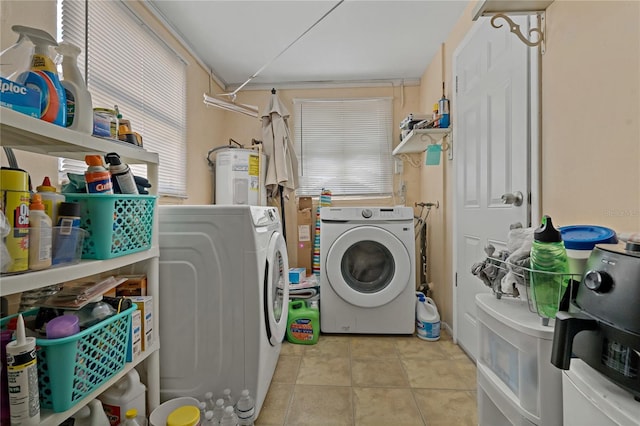 washroom with water heater, washer and dryer, and light tile patterned floors