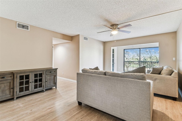 living room with a textured ceiling, ceiling fan, and light hardwood / wood-style flooring