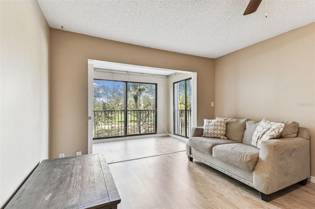 unfurnished living room featuring ceiling fan, light hardwood / wood-style floors, and a textured ceiling