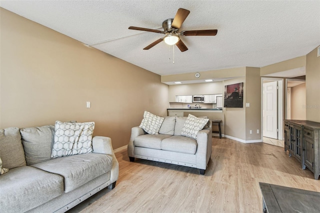 living room featuring ceiling fan, a textured ceiling, and light hardwood / wood-style floors