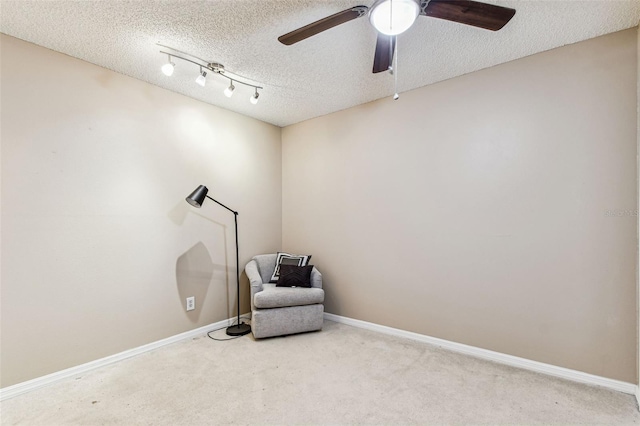 sitting room featuring ceiling fan, carpet floors, and a textured ceiling