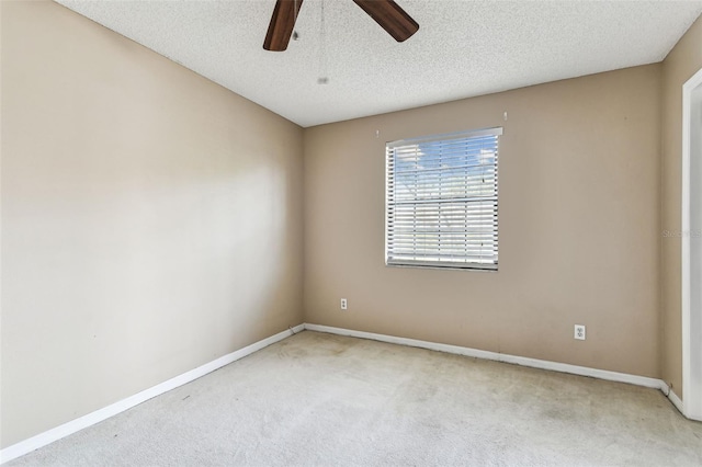 empty room featuring ceiling fan, light colored carpet, and a textured ceiling