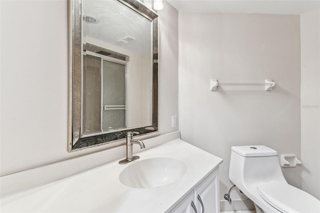 bathroom with vanity, a shower with door, and toilet