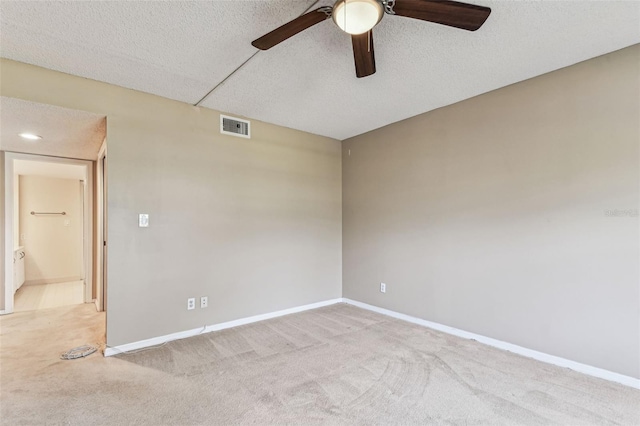 spare room with ceiling fan, light carpet, and a textured ceiling