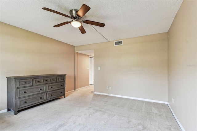 empty room featuring ceiling fan, light colored carpet, and a textured ceiling