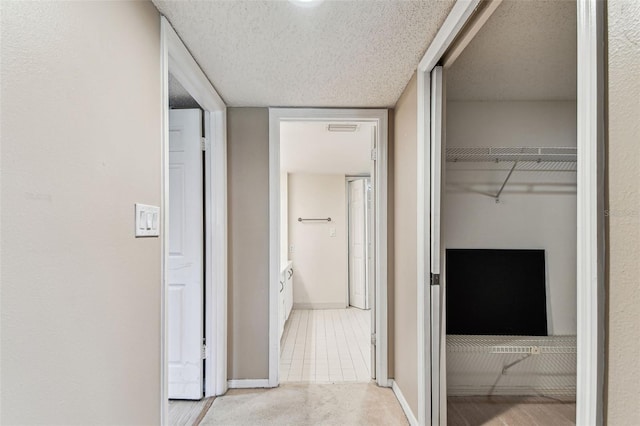 hallway with light carpet and a textured ceiling