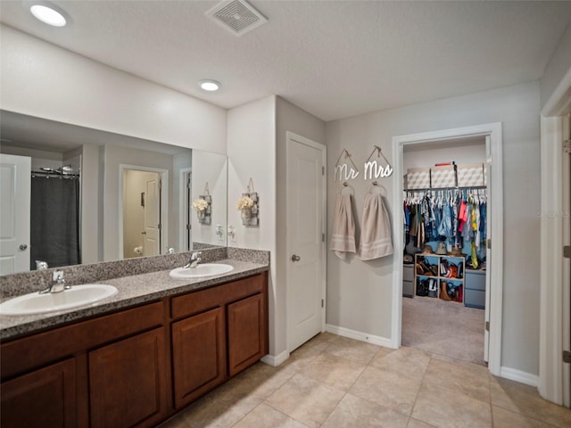 bathroom with tile patterned flooring, vanity, and a textured ceiling