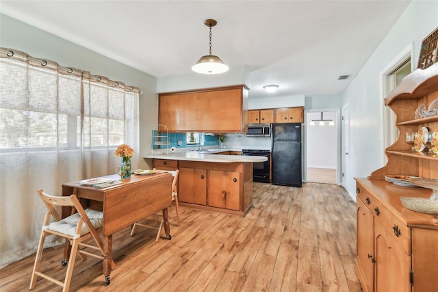 kitchen with tasteful backsplash, light hardwood / wood-style flooring, hanging light fixtures, kitchen peninsula, and black appliances