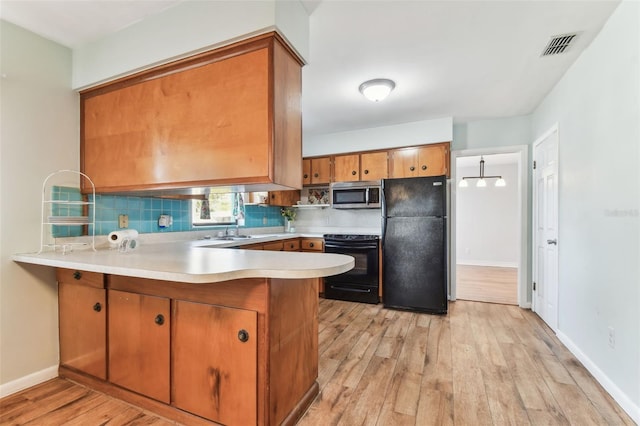 kitchen featuring tasteful backsplash, kitchen peninsula, light hardwood / wood-style flooring, and black appliances