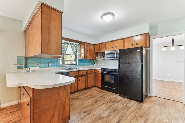 kitchen with sink, tasteful backsplash, light wood-type flooring, kitchen peninsula, and black appliances